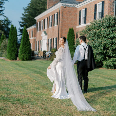 Bride and groom walking in front of a Georgian-style estate