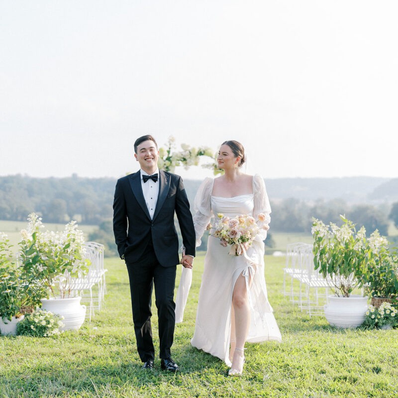 Bride and groom holding hands walking down the aisle in an outdoor, country setting