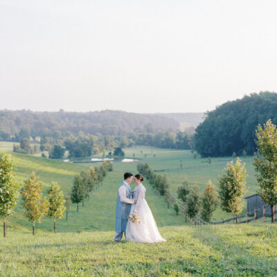 Bride and groom kissing in country field with pastoral views