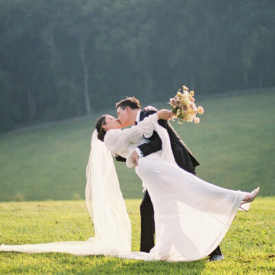 Bride and groom kissing in a green field