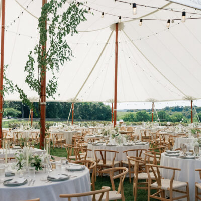 Tented wedding reception with white linen tablecloths and wishbone chairs