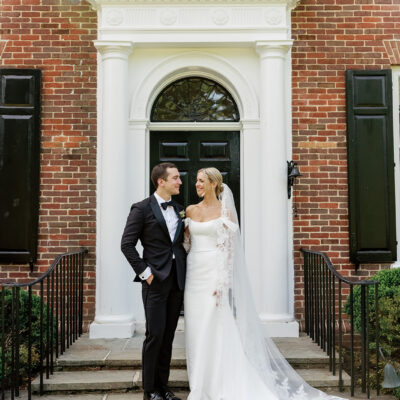 Bride and groom under doorway to brick home