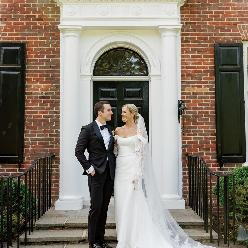 Bride and groom under doorway to brick home
