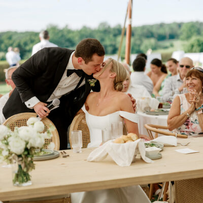 Bride and groom kissing during tented reception