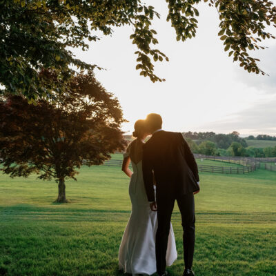 Bride and groom kissing under a tree with countryside views