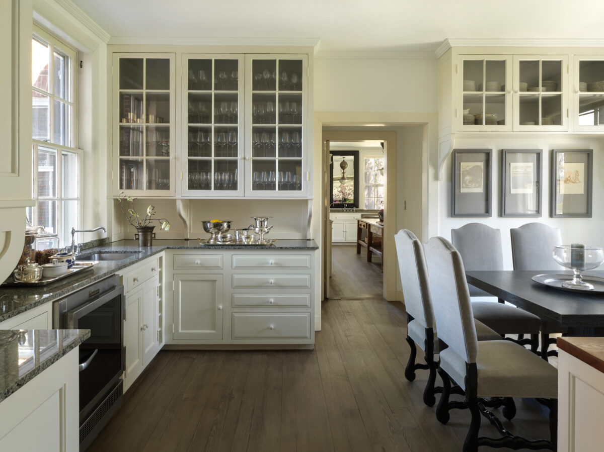 Butler's pantry with glass-front cabinets of stemware and china, opening through to the kitchen