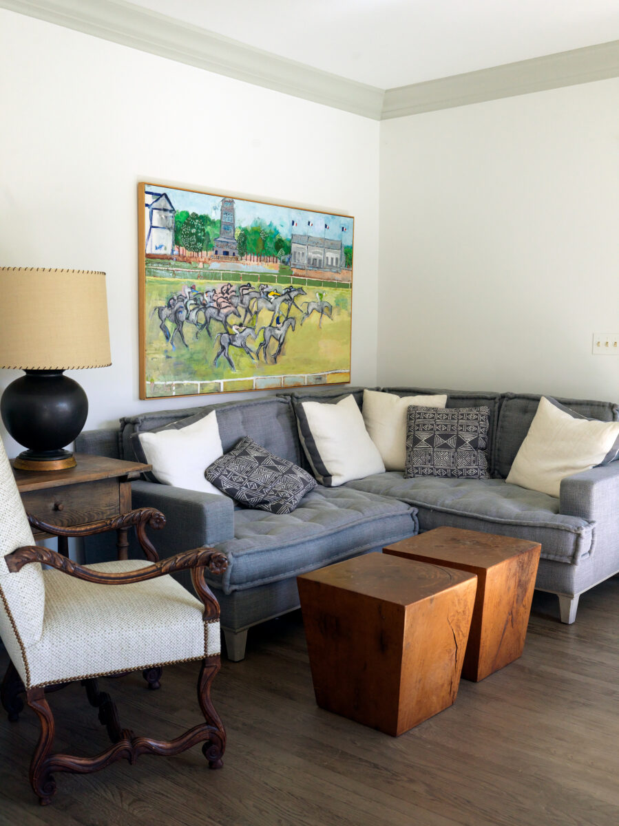 Guest house sitting area with a grey sectional and a large painting of a horse race above it