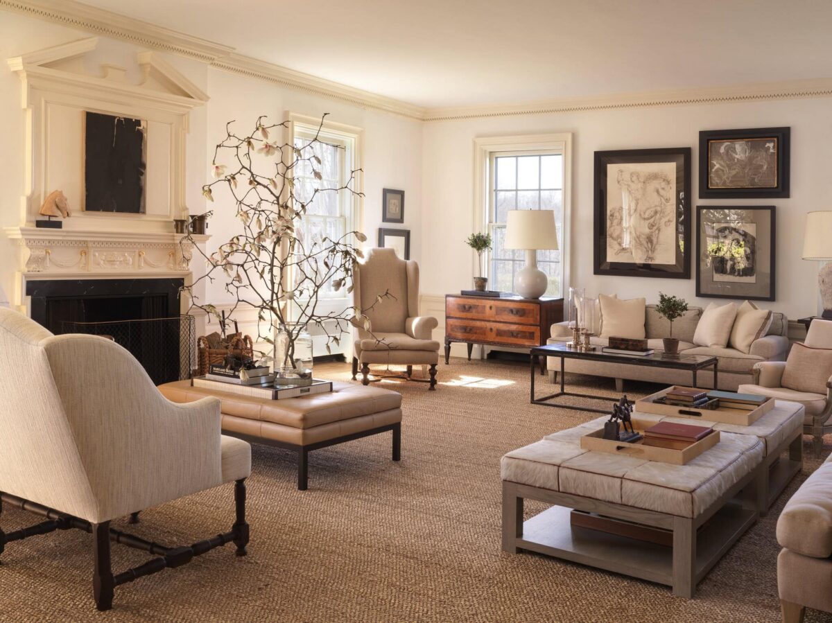 Living room with a carved marble fireplace, equestrian drawings and deep linen seating