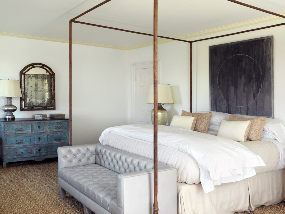 Primary bedroom with a four-poster bed, antique blue chest and a large abstract canvas.