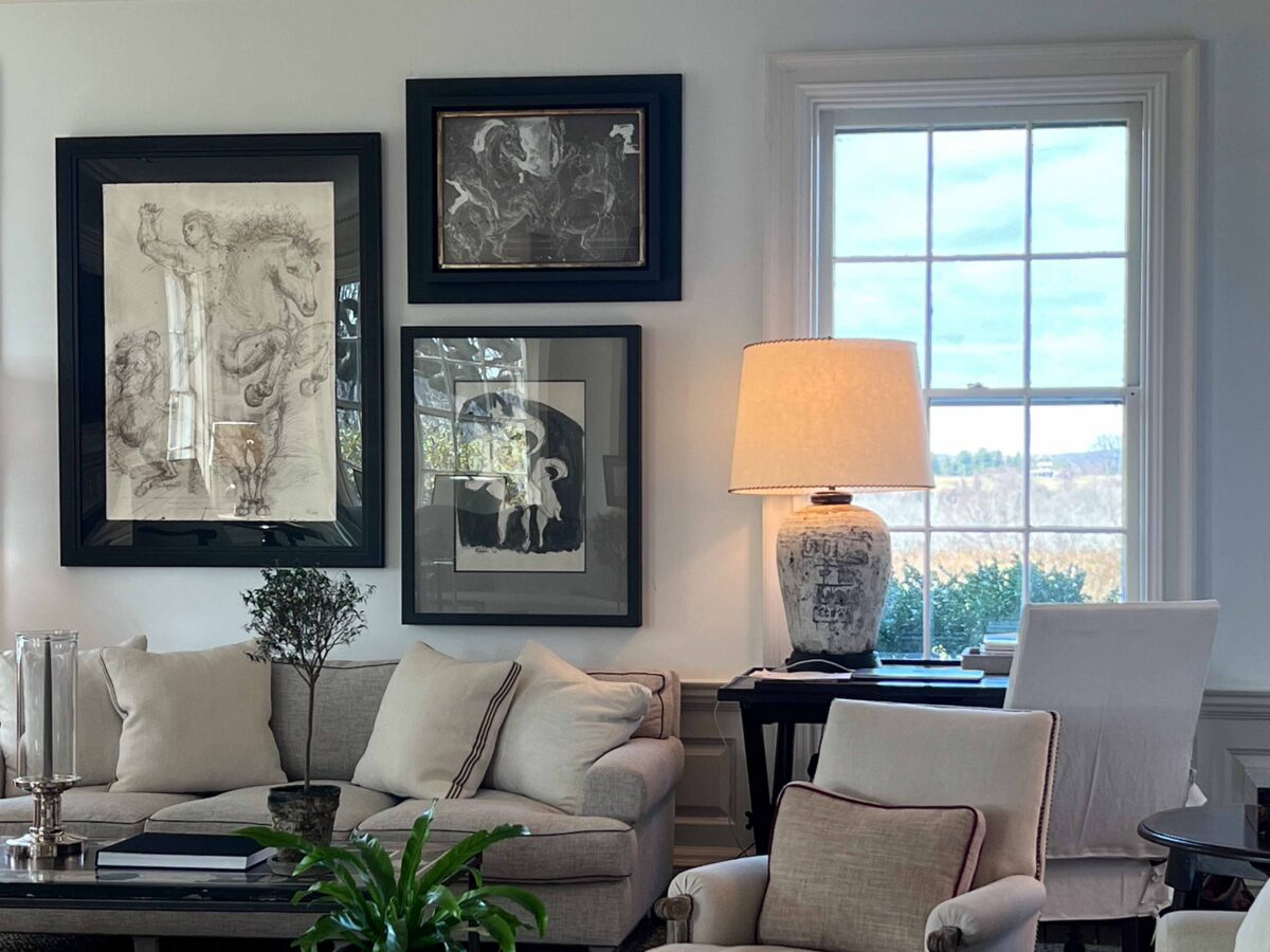 A corner of the living room with framed equestrian drawings and a window onto the countryside