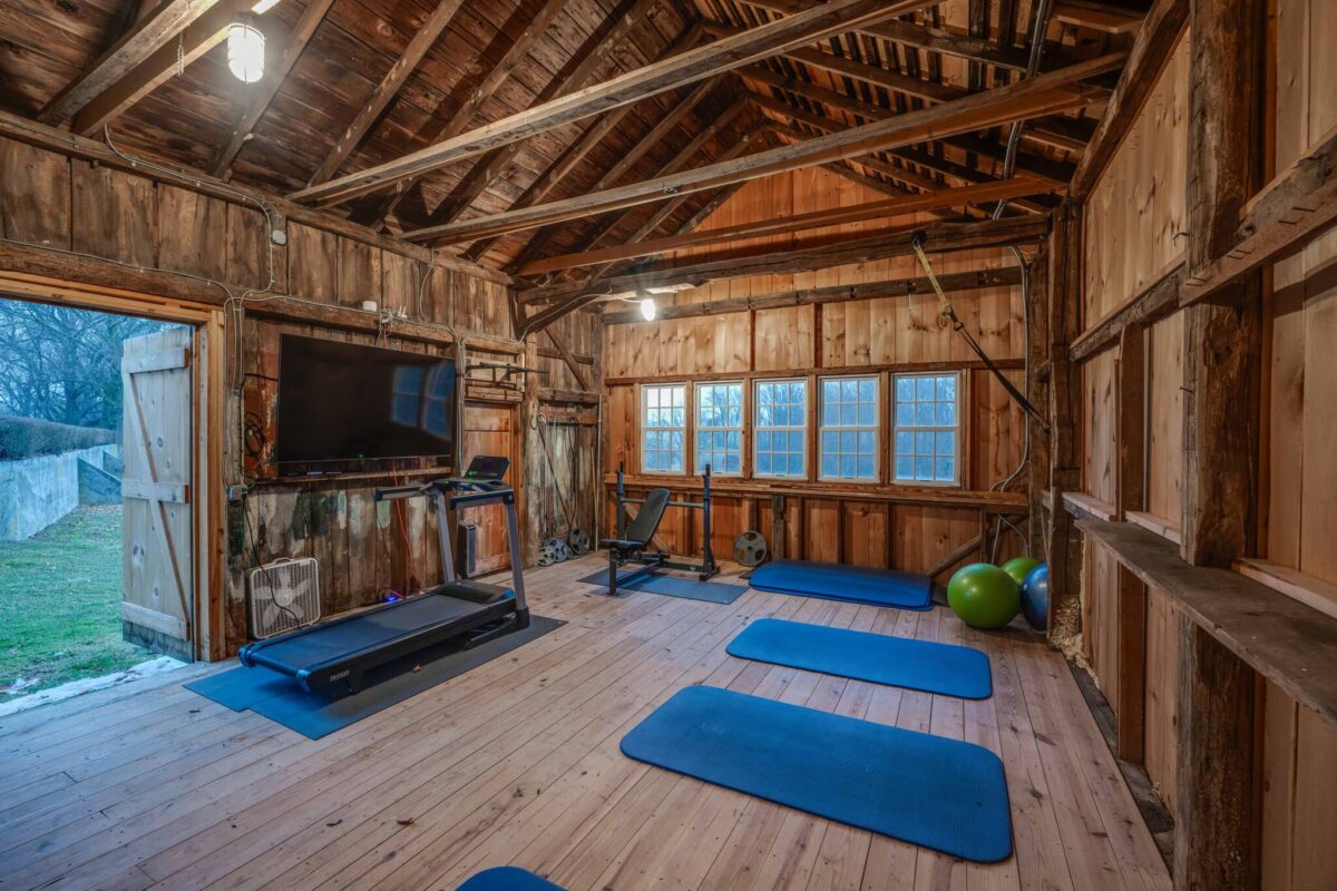 The barn fitted out as a gym, with a treadmill, weight bench and exercise mats under exposed rafters