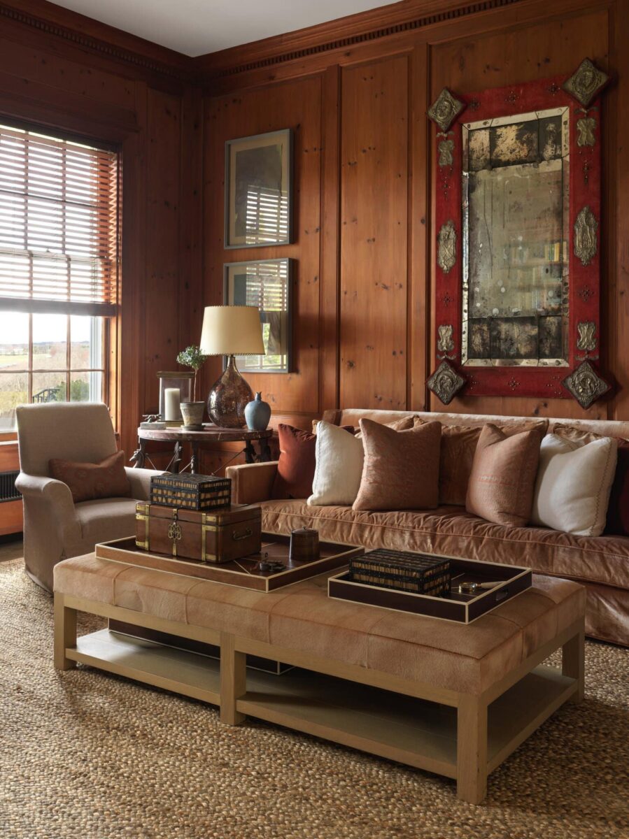Pine-paneled sitting room with a leather sofa, an antique red-framed mirror and a window over the fields